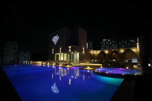 a swimming pool at night with a city in the background at Baymond Hotel in Busan