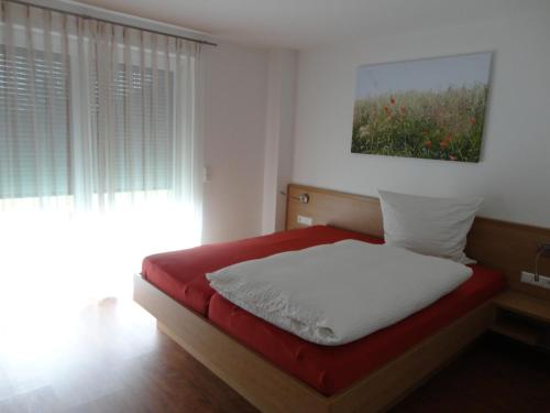 a bedroom with a red and white bed with a window at Ferienwohnung 4 in den Krautgärten in Ochsenburg