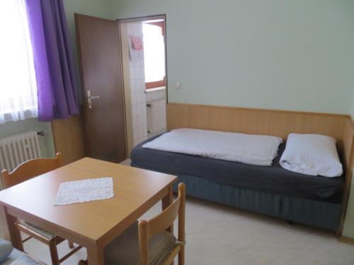 a bedroom with a bed and a table and a table and chairs at Rotes Ross in Burghaslach