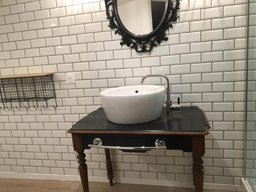 La salle de bains est pourvue d'un lavabo sur une table et d'un miroir. dans l'établissement Chambre d'hôtes Logis de Saint Jean, à Bayeux
