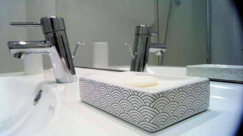 - un lavabo dans la salle de bains avec un distributeur de savon devant un miroir dans l'établissement Little Suite - Albert, à Lille