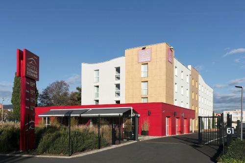 a building with a red facade and a fence at Hotel Clermont Estaing in Clermont-Ferrand