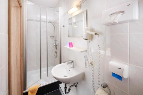 a white bathroom with a sink and a shower at Gasthof Zum Hobel in Drolshagen