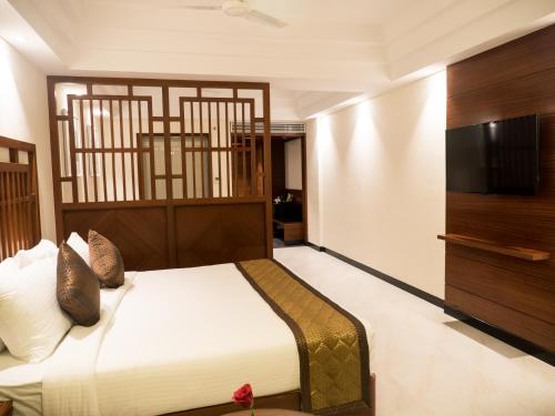 a bedroom with a large bed and a flat screen tv at MM Legacy - A Bergamont Hotel, Kanchipuram in Kanchipuram
