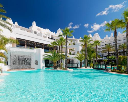 a swimming pool in front of a large white building at H10 Estepona Palace in Estepona