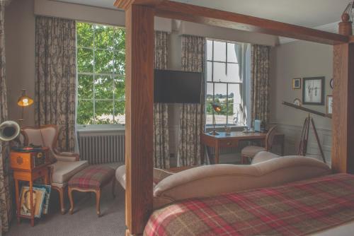 a bedroom with a bed and a desk and window at De Vere Wokefield Estate in Reading
