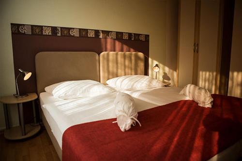 um quarto com uma cama grande com lençóis brancos e almofadas em Dithmarscher Hof em Itzehoe