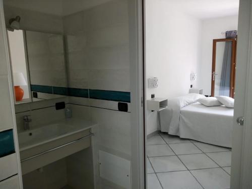 um quarto com uma cama, um lavatório e um espelho em Hotel Alador em Budoni