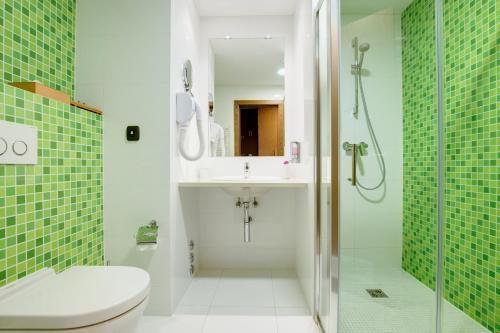 a bathroom with a toilet and a sink and a shower at Emerald Hotel in Prishtinë