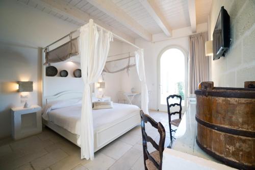 a bedroom with a white canopy bed and a window at Masseria Agrituristica Lama San Giorgio in Rutigliano