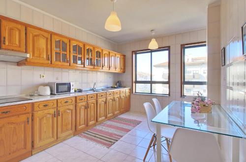 a kitchen with wooden cabinets and a glass table at SResende Place Aveiro in Aveiro