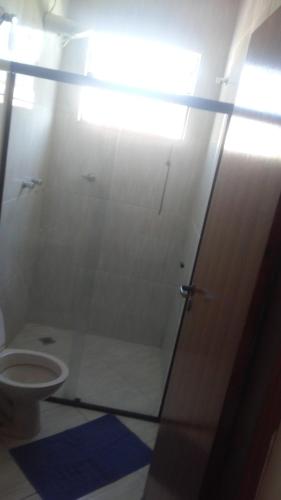 a bathroom with a toilet and a glass door at Casa e Suites in Aparecida