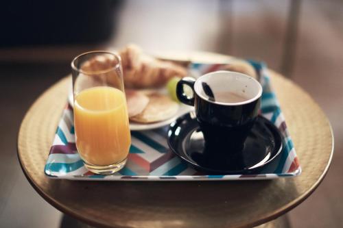 a tray with a cup of coffee and a glass of orange juice at Le Central Boutique Hôtel in Beaune