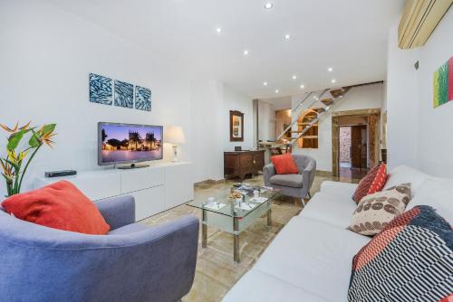 a living room with a white couch and a tv at Ca Se Predine - Mediterranean Styled Townhouse in Alcudia
