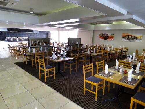 a dining room with wooden tables and chairs at African Sky Harrismith Inn in Harrismith