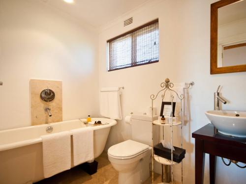 a bathroom with a tub and a toilet and a sink at Leeuwenbosch Shearers Lodge - Amakhala Game Reserve in Buyskloof
