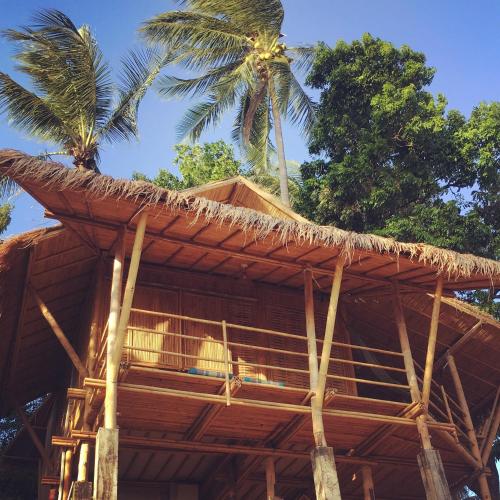 a straw roof on top of a building with palm trees at Kalulushi Bungalows in Haad Pleayleam