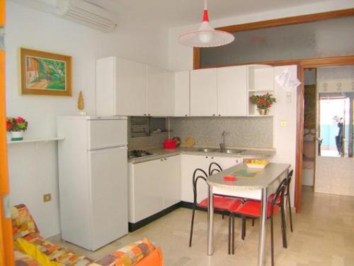 eine Küche mit weißen Schränken sowie einem Tisch und Stühlen in der Unterkunft Appartamenti Padoan in Sottomarina
