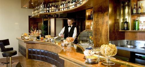 a man in a tuxedo standing behind a bar at Sina Brufani in Perugia