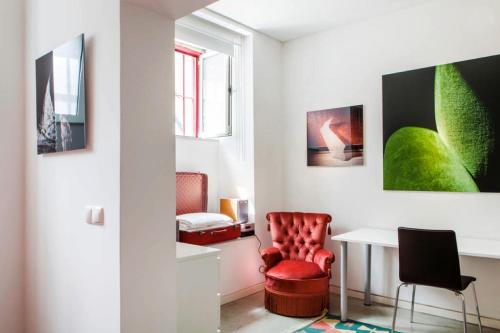 a living room with a red chair and a table at Art Gallery Apartment in Lisbon
