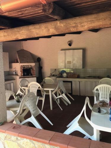 a group of white chairs and tables in a kitchen at Sweet Home & Apartments in Fontane Bianche