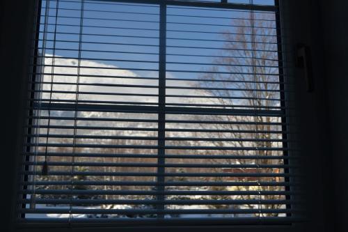 a window with blinds on it with a view of a building at Greenwood hotel in Smokovce