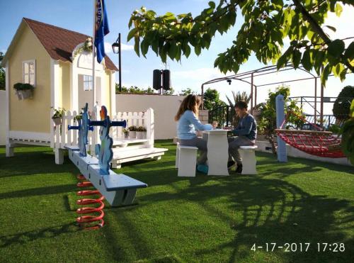 a man and woman sitting at a table in a park at Apartments Gina in Trogir