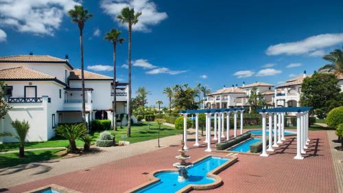 a villa with a swimming pool and palm trees at Leo San Bruno in Isla Canela