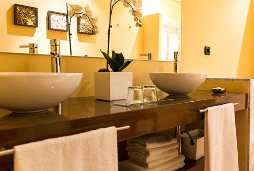 a bathroom with a counter with two sinks and towels at La casona de los yebenes in Los Yébenes