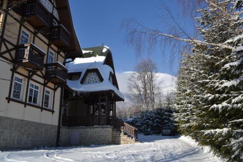 a house with snow on the side of it at Greenwood hotel in Smokovce
