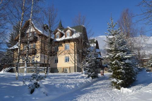 a large house with snow in front of it at Greenwood hotel in Smokovce
