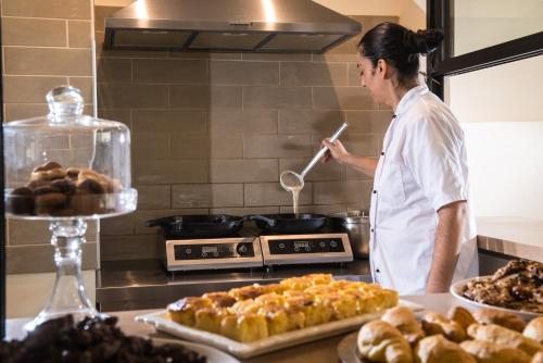 a woman standing in a kitchen preparing food at Infinity City Boutique Hotel in Heraklio Town