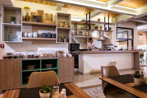a kitchen with tables and a woman in the kitchen at Infinity City Boutique Hotel in Heraklio Town