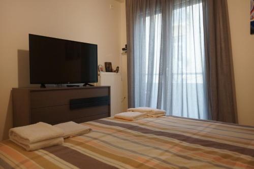 a bedroom with a television and a bed with towels at Georgina's cozy apartment -Metropolitan Hospital- in Piraeus
