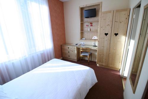 a bedroom with a bed and a desk and a television at Alti'Pic Hôtel in Le Mont-Dore