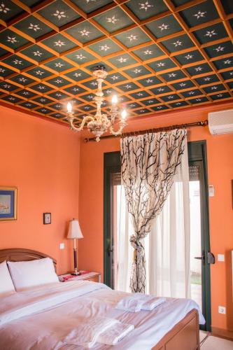 a bedroom with orange walls and a ceiling with a chandelier at 4-seasons pool villa near Meteora in Tríkala