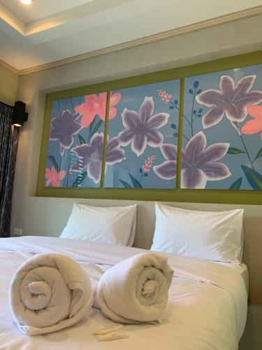 a bedroom with a bed with two towels on it at โรงแรมมาลินี in Surin