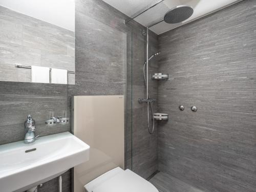 een badkamer met een douche, een toilet en een wastafel bij LAAX Homes - Casa Zundra in Flims