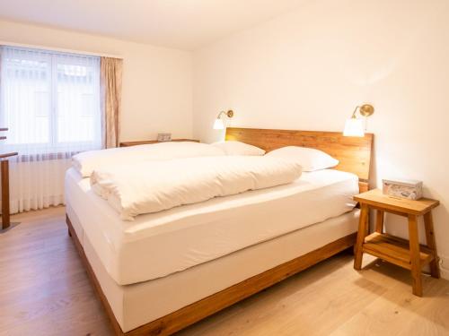 een groot wit bed in een kamer met een raam bij LAAX Homes - Casa Zundra in Flims