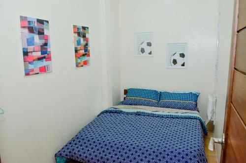a bedroom with a bed with blue sheets and pictures on the wall at MAILZ HAVEN BEAUTIFL 3BR MODERN APRT NEAR SM DOOR-C in Davao City