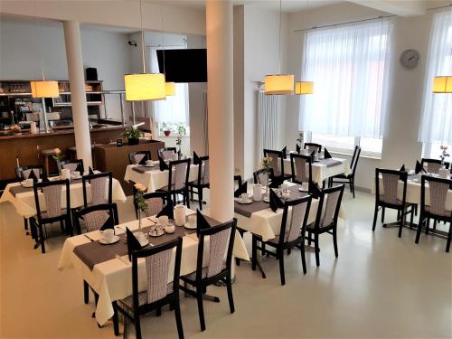 ein Esszimmer mit Tischen, Stühlen und Lampen in der Unterkunft Hotel Weissach Am Neuenbühl in Weissach