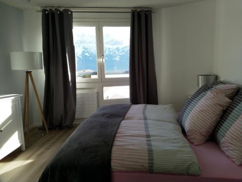 a bedroom with a bed and a window with mountains at Swiss Seeblick Apartment mit Hotelanbindung in Beatenberg
