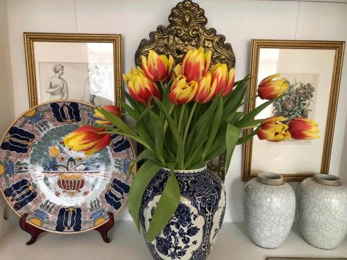 a vase with flowers in it on a table with pictures at Canal View B&B Amsterdam in Amsterdam