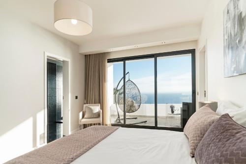 een slaapkamer met een bed en een groot raam bij Sky Villa by An Island Apart in Funchal