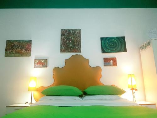a bedroom with a bed with green pillows and paintings on the wall at B&B Platamon in Naples