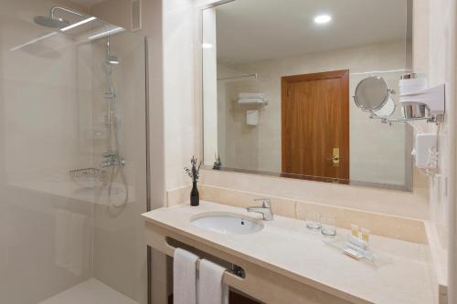 uma casa de banho com um lavatório e um chuveiro com um espelho. em Elba Madrid Alcalá em Madri