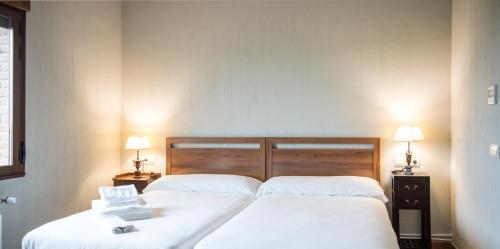 a bedroom with two beds with white sheets and two lamps at Casa Rural Pilón del Fraile in Oropesa