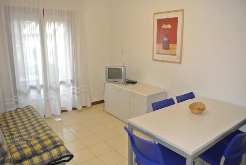 a room with a table and chairs and a tv at Condominio LISA in Lignano Sabbiadoro