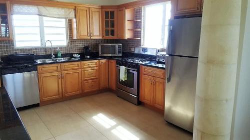 a kitchen with wooden cabinets and a stainless steel refrigerator at White Sands Anguilla - Sea in Blowing Point Village