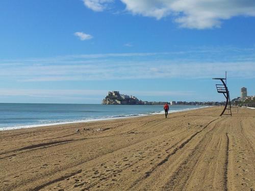 a man walking on a beach with a sculpture at Hotel Bodegón de Peñíscola in Peñíscola